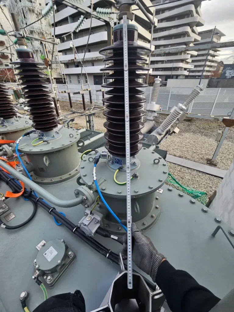 Technicien effectuant une mesure sur isolateur de poste haute tension.