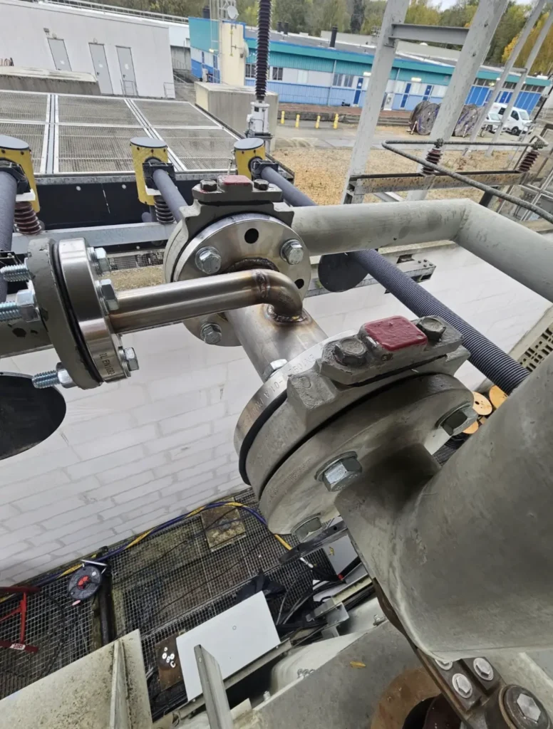 Raccords inox et brides installés sur la tuyauterie d’un transformateur haute tension