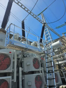Prestation de HTB, Height Technician in Building, pour la conception et la pose d'un équipement de protection collective : passerelle avec garde-corps, munie d'un support d'échelle parallèle, pour un accès aux aéros d'un transformateur électrique. Vue sur les deux dispositifs antichute.