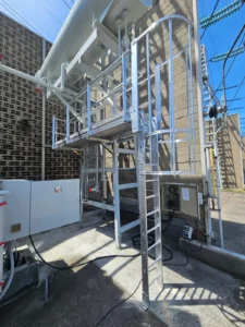 Intervention de HTB, Height Technician in Building, pour la réalisation et la mise en place d'un équipement de protection collective (dispositif antichute) contre les chutes de hauteur, à savoir une passerelle avec garde-corps, munie d'une échelle à crinoline. Prestation réalisée sur un transformateur électrique haute tension.