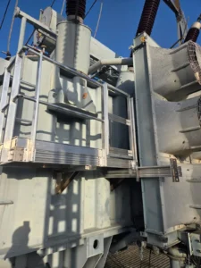 Height Technician in Building intervient pour l'installation d'un équipement de protection collective sur un transformateur électrique. Il s'agit là d'une passerelle avec garde-corps, dans le cadre d'une prestation d'assujettissement