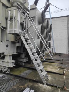 Intervention de la sarl Height Technician in Building (H.T.B) pour l'installation de moyens d'accès sur un transformateur électrique. Il s'agit là de la mise en place d'un escalier d'accès à la passerelle, pour la maintenance transformateur. Intervention dans le cadre de travaux de sécurisation d'un transformateur électrique contre les chutes de hauteur.