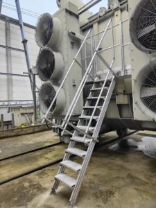 Intervention de la sarl Height Technician in Building (H.T.B) pour l'installation de moyens d'accès sur un transformateur électrique. Il s'agit là de la mise en place d'un escalier d'accès à la passerelle, pour la maintenance transformateur. Intervention dans le cadre de travaux de sécurisation d'un transformateur électrique contre les chutes de hauteur.