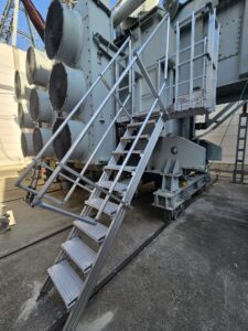 Intervention de la sarl Height Technician in Building (H.T.B) pour l'installation de moyens d'accès sur un transformateur électrique. Il s'agit là de la mise en place d'un escalier d'accès à la passerelle, pour la maintenance transformateur. Intervention dans le cadre de travaux de sécurisation d'un transformateur électrique contre les chutes de hauteur.