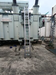 Intervention de Height Technician in Building pour l'installation d'une plateforme de départ d'échelle. Il s'agit là d'un moyen d'accès à la toiture d'un transformateur électrique. Intervention dans le cadre de travaux de sécurisation d'un transformateur contre les chutes de hauteur.