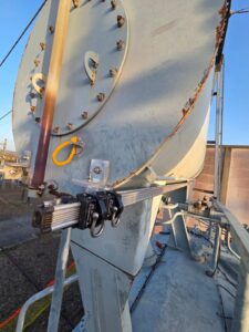 Intervention de Height Technician in Building pour la mise en place d'équipements de protection individuelle. Il s'agit là de mettre en place une ligne de vie horizontale rail, maintenue par deux équerres de rail. L'installation s'est faite sur le conservateur d'un transformateur. Ce sont là des dispositifs d'ancrage contre les chutes de hauteur.