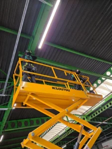 Intervention de Height Technician in Building pour la réalisation et la pose d'une ligne de vie rail sur plafond. Les deux techniciens sont élevés grâce à une nacelle. Il s'agit là de l'installation d'un équipement de protection individuelle contre les chutes de hauteur.