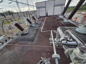 Intervention de Height Technician in Building pour la mise en place d'équipements de protection individuelle. Il s'agit là de mettre en place une ligne de vie câble. La ligne de vie câble est fixée au moyen de potelets, sur la toiture d'une enceinte insonorisée. Ce qui assure la sécurité de l'utilisateur lors de travaux en hauteur.